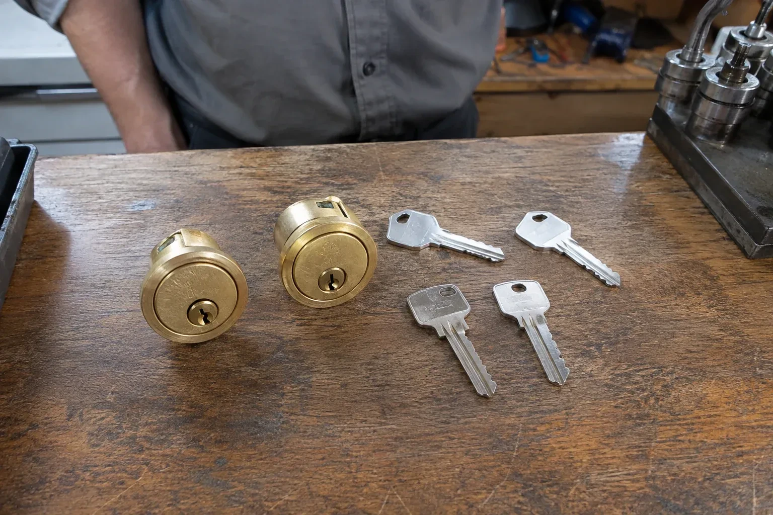Two detached brass lock cylinders and four house keys on a wooden counter. — Lock Rekeying, St. Catharines